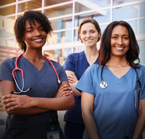 A group of happy nurses in front of a medical facility
