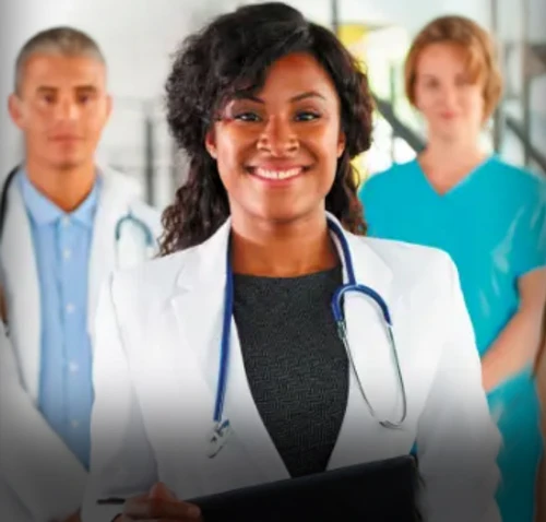 A medical professional in white scrubs and stethoscope smiling