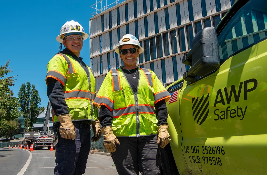 Two employees smiling while working together at a jobsite.