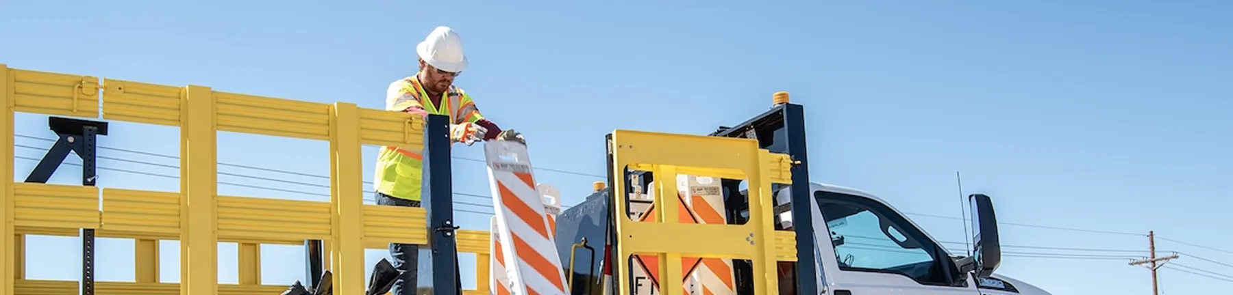 An AWP employee unloading traffic control signage from a work truck.