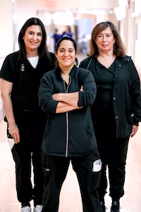 Three healthcare professionals in black scrubs standing in a medical facility hallway