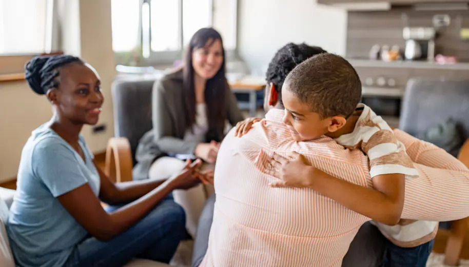  	A family hugging in a therapistâ€™s office.