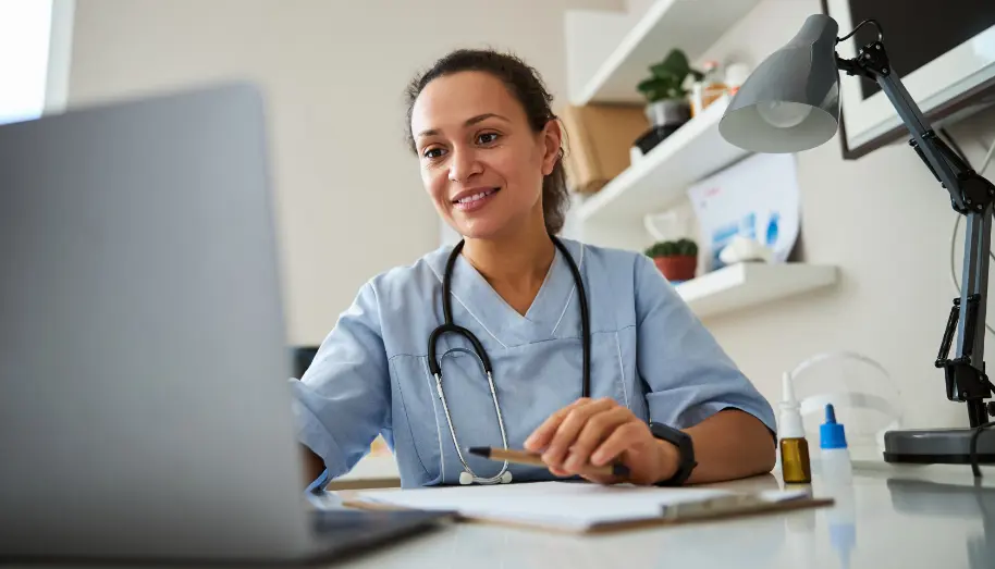  	A healthcare professional sitting at a desk using a computer.