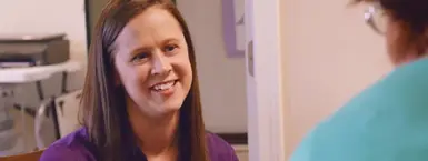 A smiling, dedicated CareSource care coordinator in an office setting. (Mobile)