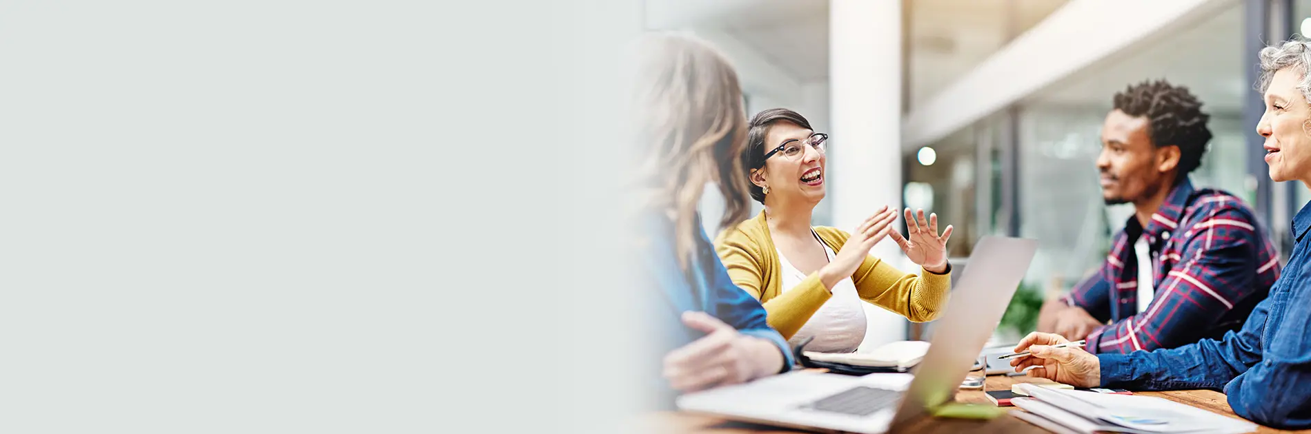 A senior female executive collaborates with three colleagues at a conference table.