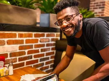 A Cheddar’s team member smiling and cleaning a table.