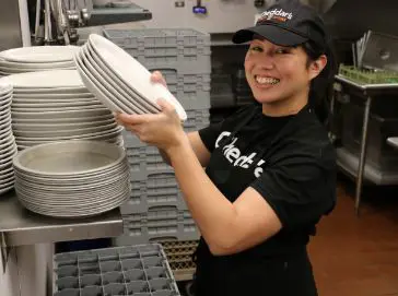 A Cheddar’s team member smiling and holding a stack of plates.