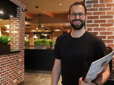 A Cheddar’s team member smiling and holding menus.