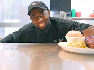 A Cheddar's team member smiling while cooking a meal.