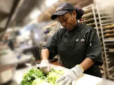 A Cheddar's team member smiling and preparing vegetables.