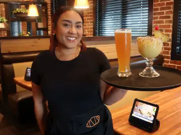 A Cheddar’s team member smiling and holding drinks.