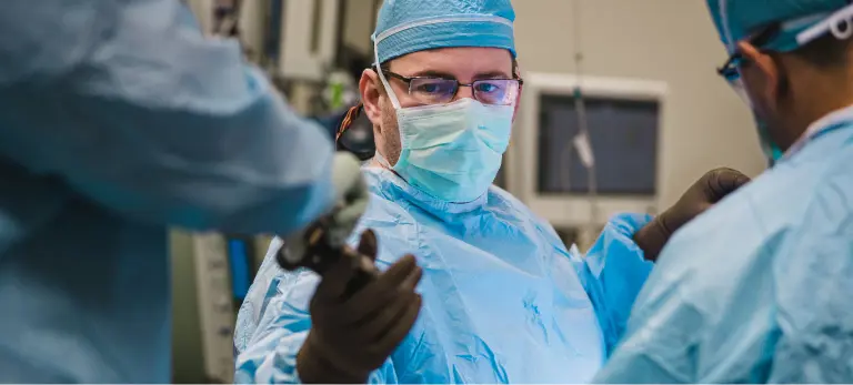 A medical professional taking a piece of medical equipment from a colleague.