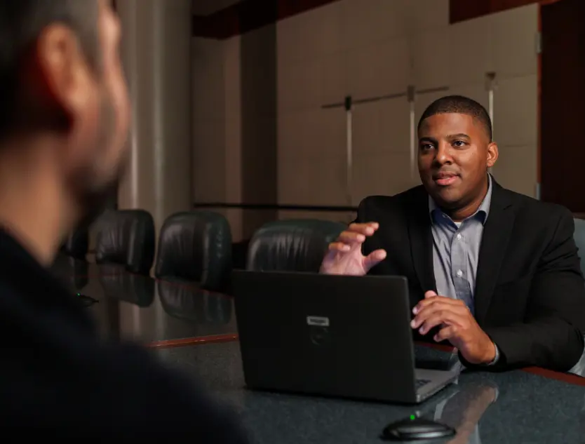 Two individuals talking in a conference room.