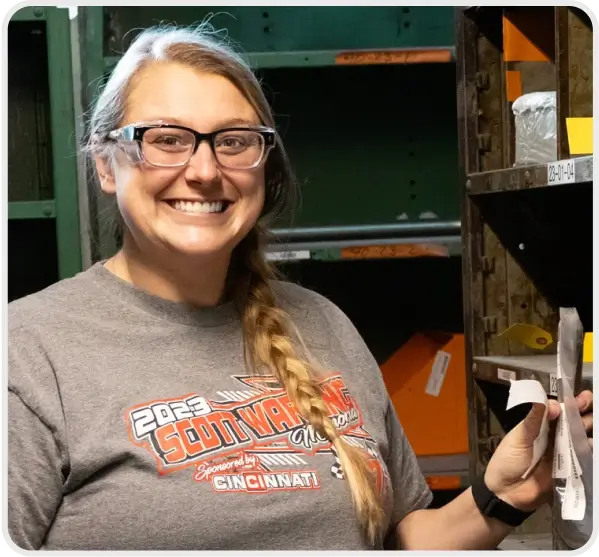 A Cincinnati Incorporated team member holding supplies and grinning.