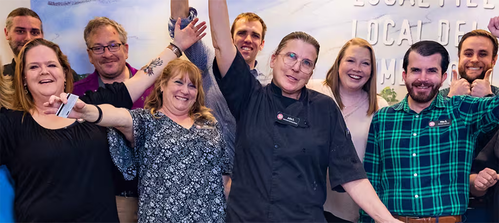 A large team of Dierbergs associates standing together and smiling with their arms raised
