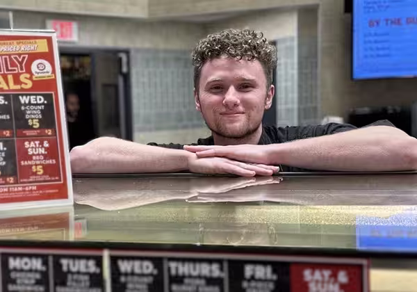 Two deli/seafood employees holding frozen fish and smiling