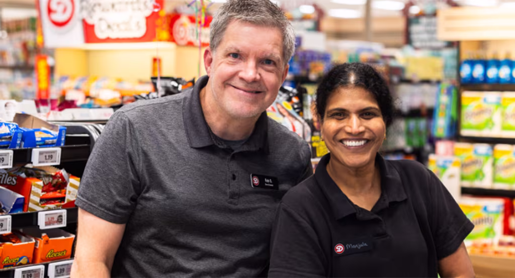 A retail associate standing next to a store manager, both smiling.