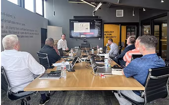 A table with eight ECAM corporate professionals sitting and reviewing a presentation.
