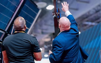 Two ECAM professionals with their backs toward the camera, standing together in discussion while analyzing equipment.