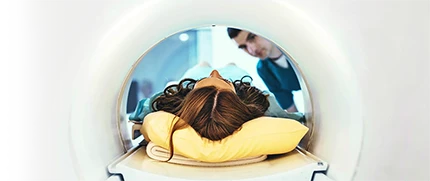 A patient going through an MRI machine while an MRI technologist waits.