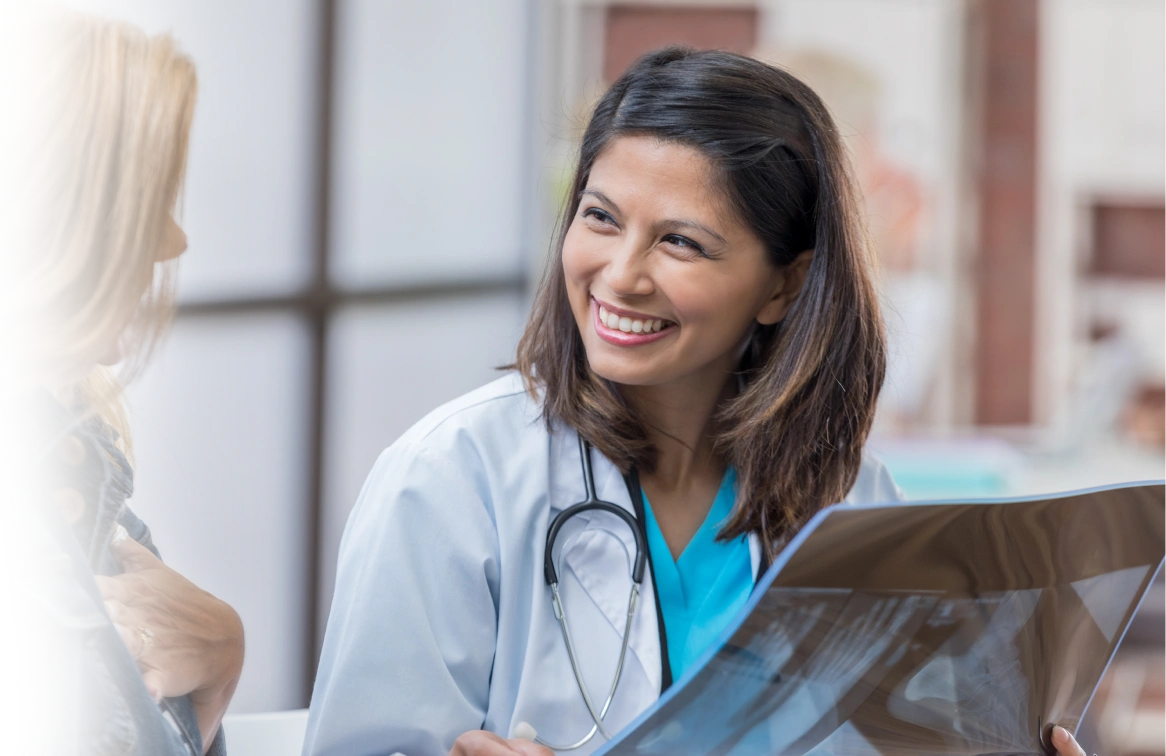 A Fairfax radiology Physician smiling as she reviews x-rays with another healthcare professional.