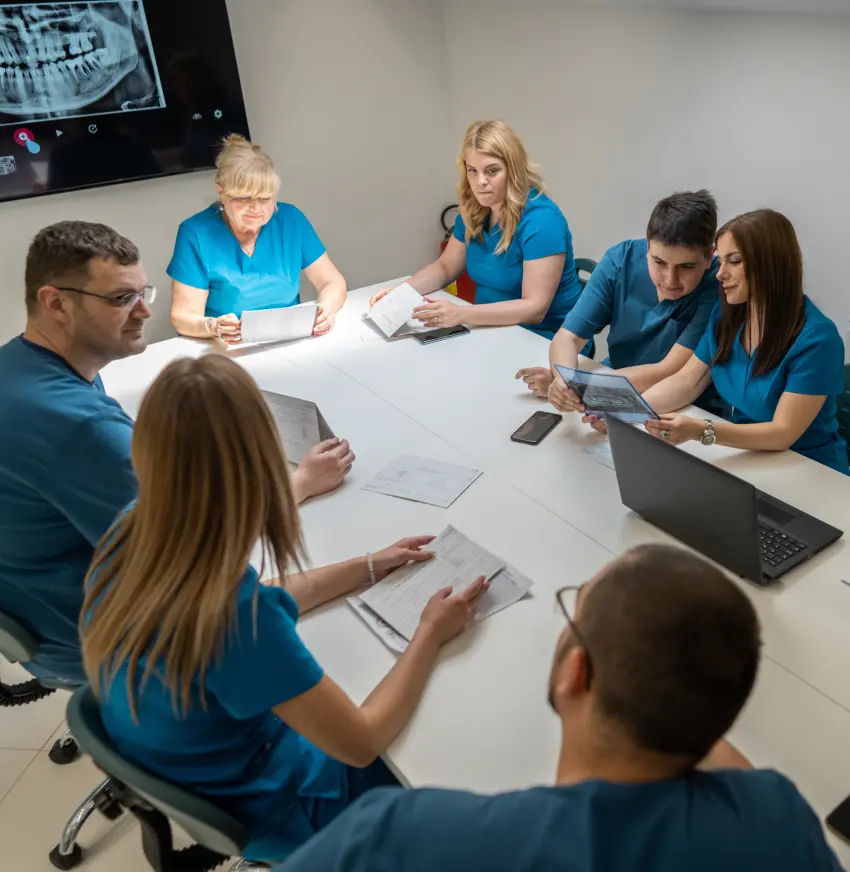 A team of dentists sitting around a table in discussion.