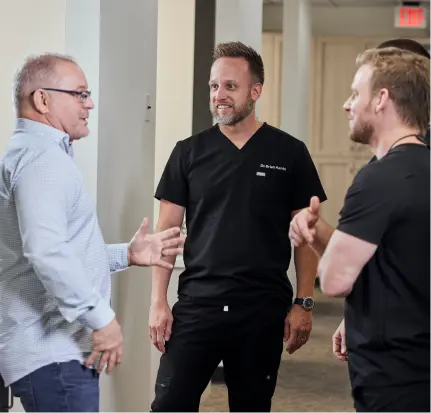 Two dentists speaking with a business partner at Gen4 Dental Partners.