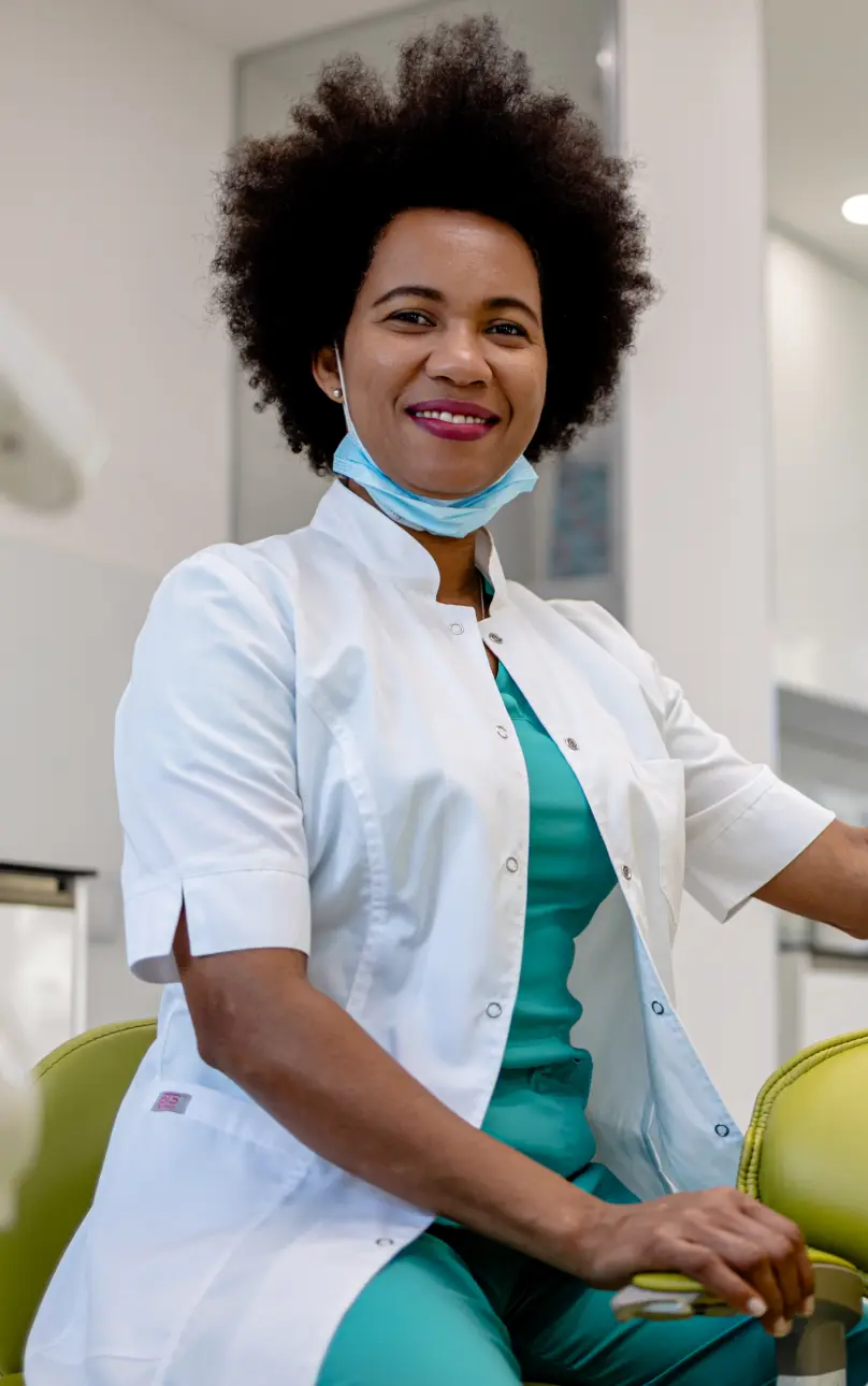 A smiling dental hygienist sitting in a procedure room.