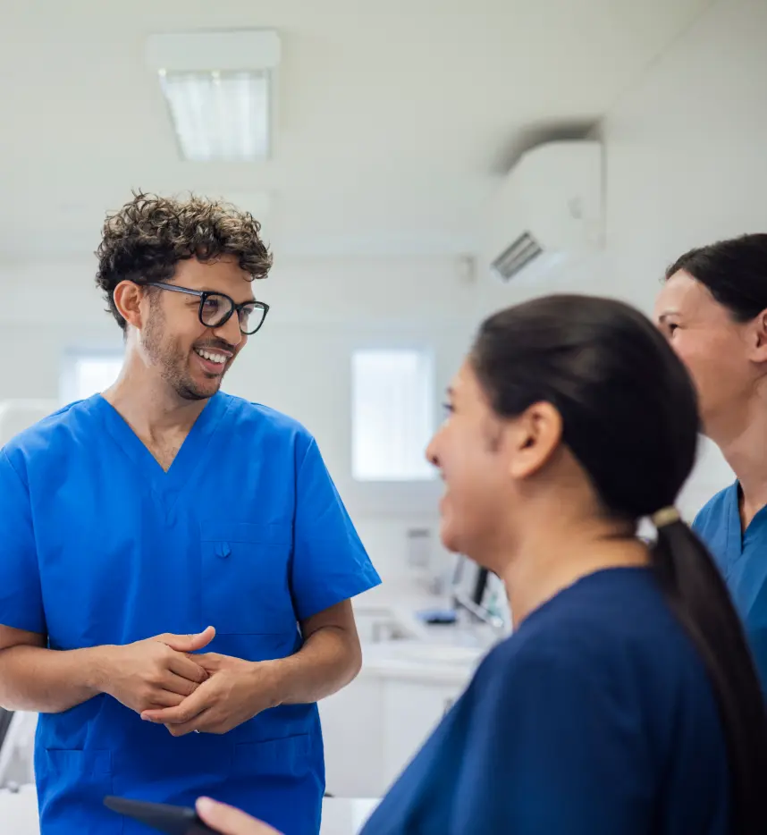 Three dental assistants laughing and talking.