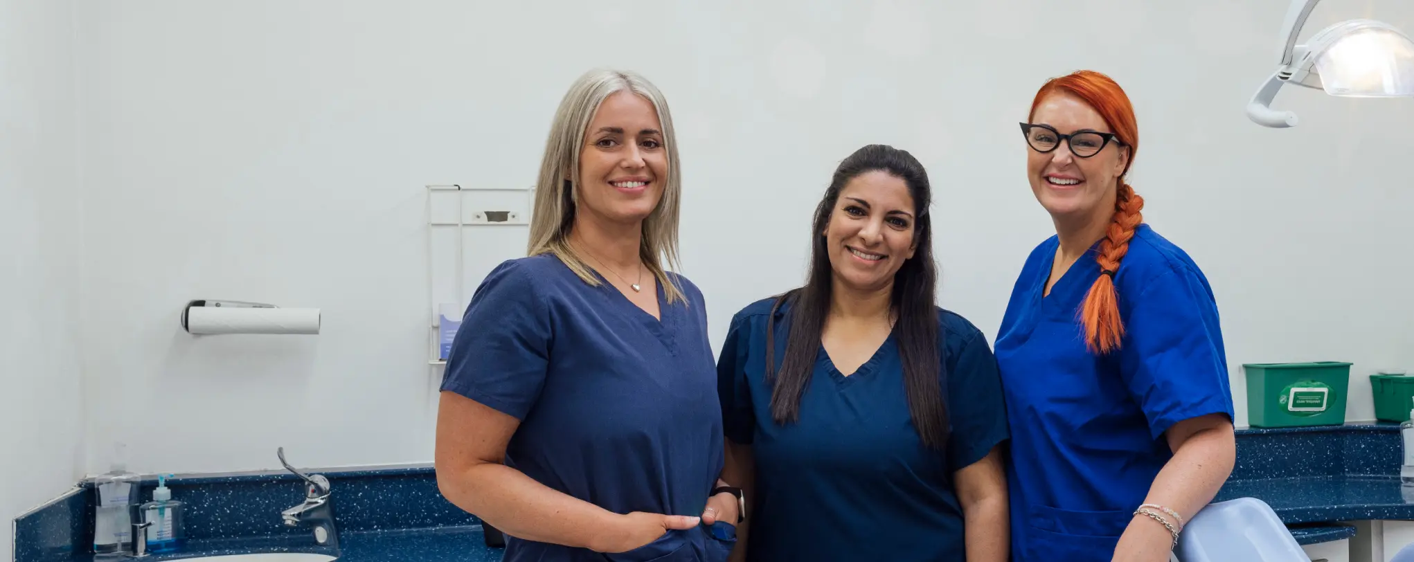 Three dental assistants standing next to each other and smiling.