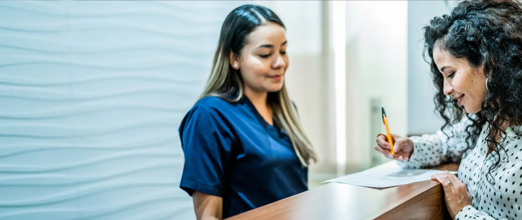 A receptionist helping a patient with paperwork.