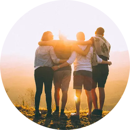 People standing with their arms around each other gazing at a sunset.