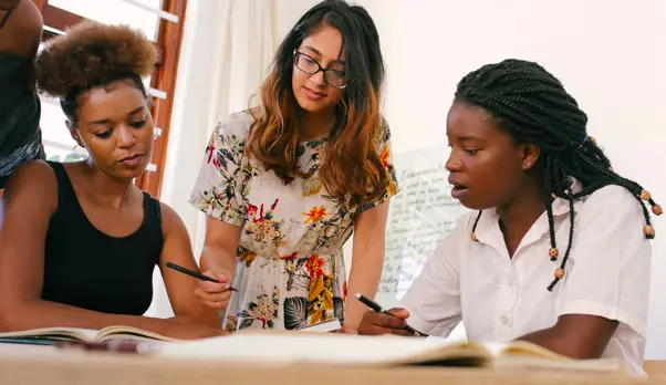 Three female executives collaborate on a project in an office setting.