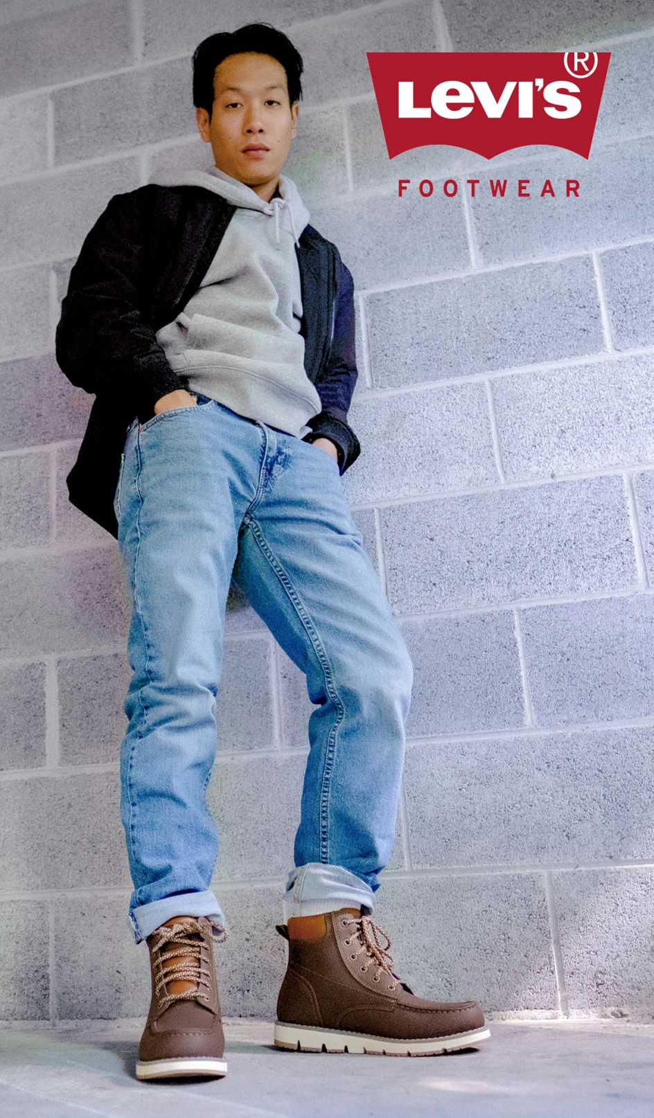 Model wearing Levi’s Footwear hiking shoes, posing by a brick wall. 