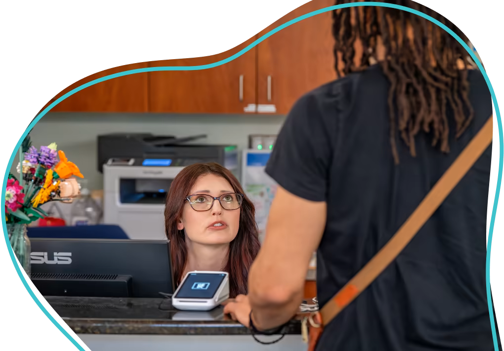 Receptionist assisting a patient at the front desk.