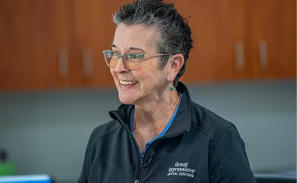 Smiling dental care professional wearing glasses.