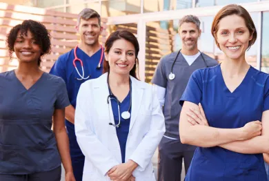 Healthcare team members smiling in front of a healthcare facility.