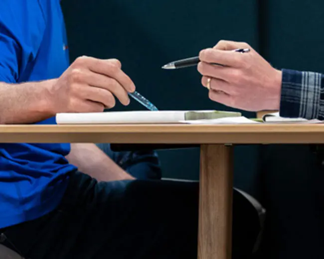 Closeup of two individuals on a meeting focusing on their hands.
