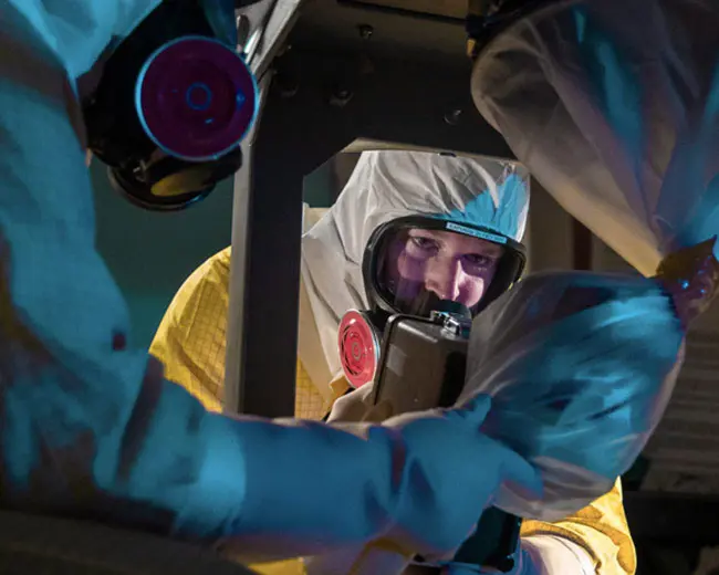 Plutonium Missions employee in protective suit at work.