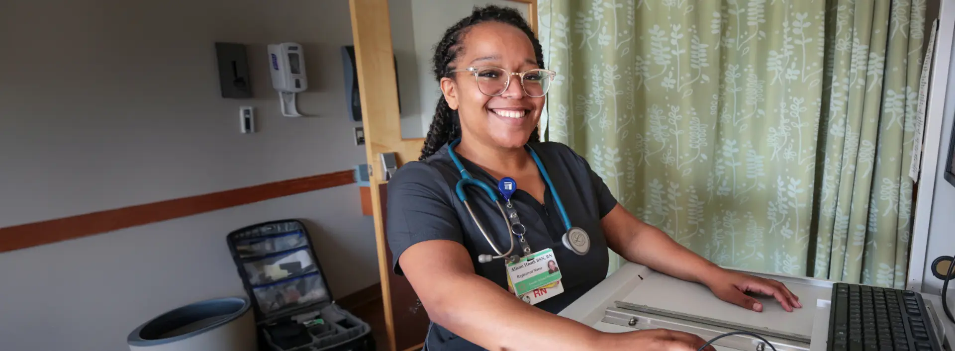 A Brown University Health professional smiling as she works at a standing desk.