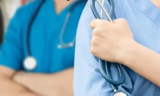 A healthcare professional grasping their stethoscope.