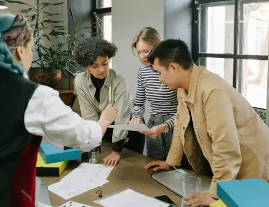 A group of employees discussing documents in a conference room.