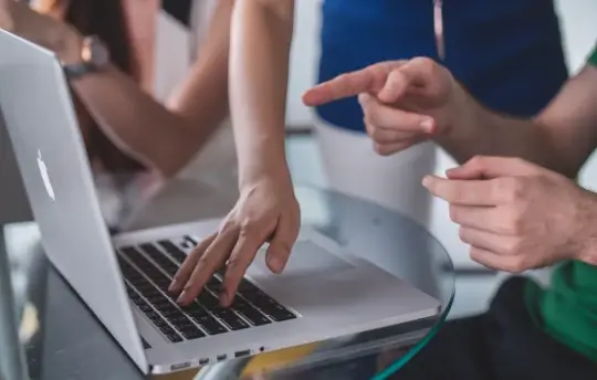 Hands working at a laptop together.