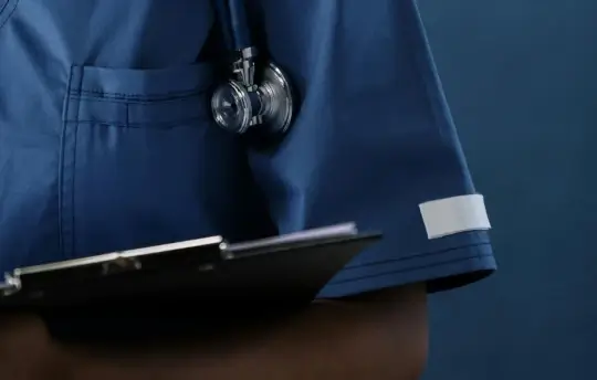 An up close view of a healthcare professional holding a clipboard.