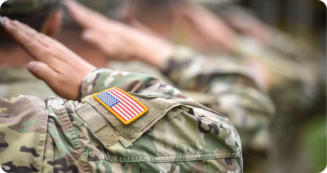 U.S. Army servicemembers in fatigues standing in a row with their arms in salute.