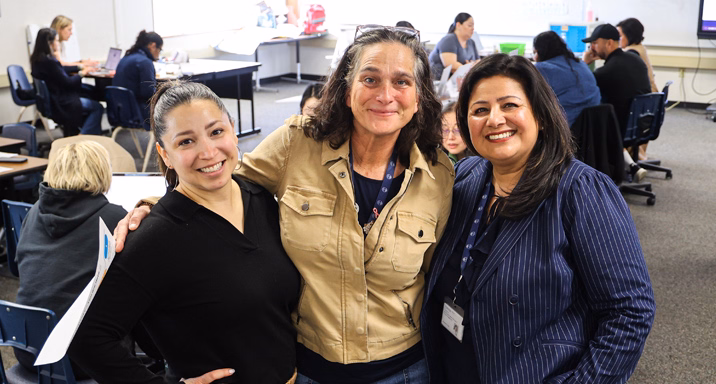 A group of adults in graduation gowns, smiling for the camera.