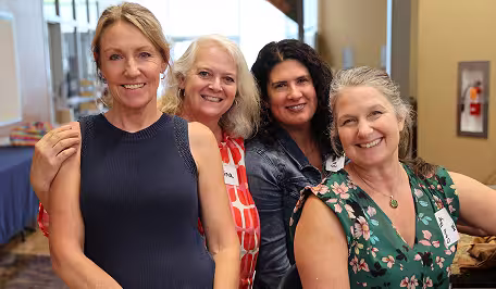 Four NVUSD employees wearing business casual clothes smiling for the camera.