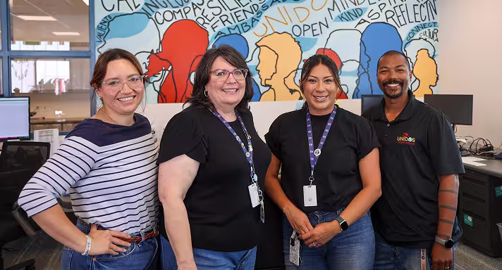 Four teachers in the computer lab, smiling for the camera.
