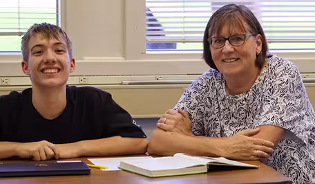 A teacher and student smiling at a desk.