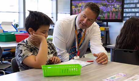 A principal wearing a green shirt, smiling at her desk.